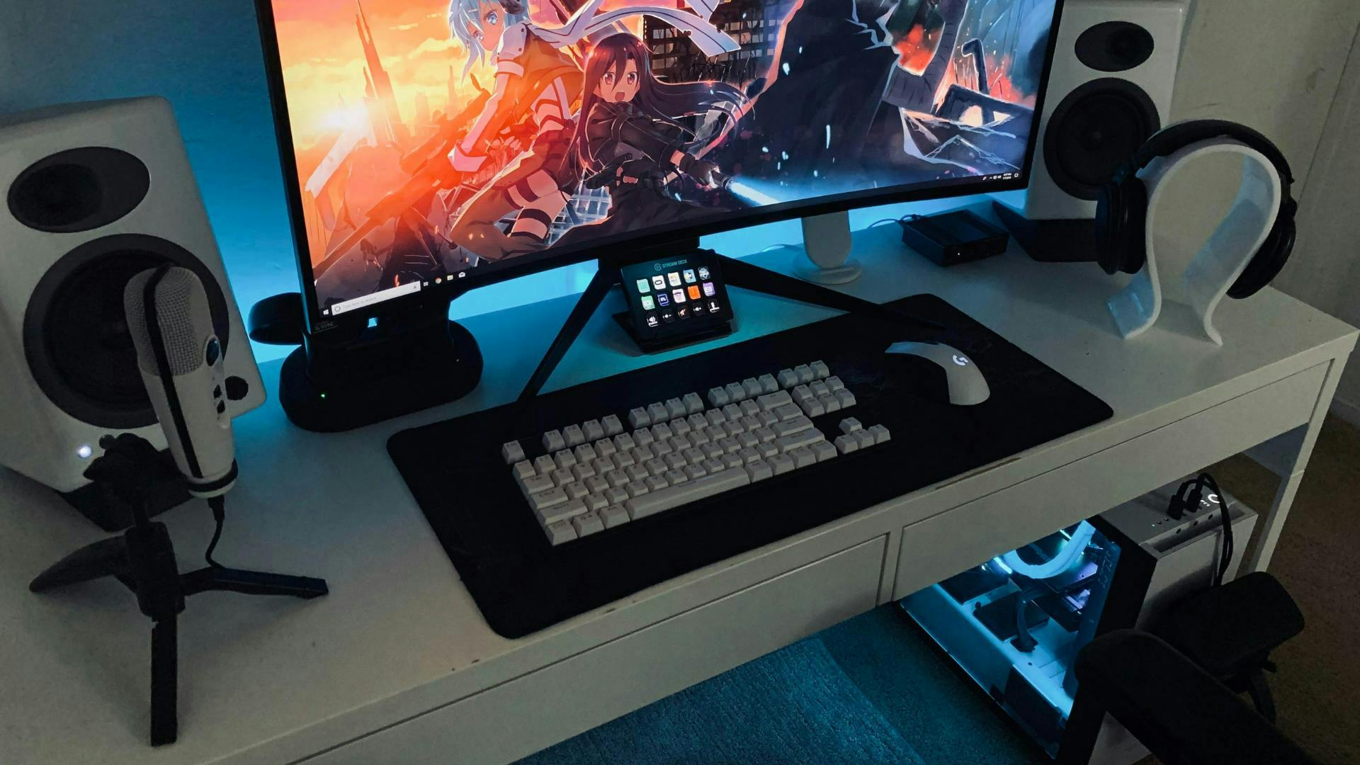 Ein weiß ausgelegtes Gaming Setup mit Gaming PC, ultrawide Monitor, Headset, Streaming-Mikrofon und weißen Lautsprechern