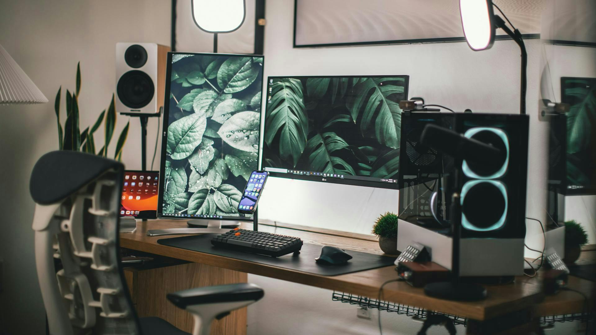 A desk with a gaming PC, two monitors and a gaming keyboard is decorated in natural shades of beige, light brown and green