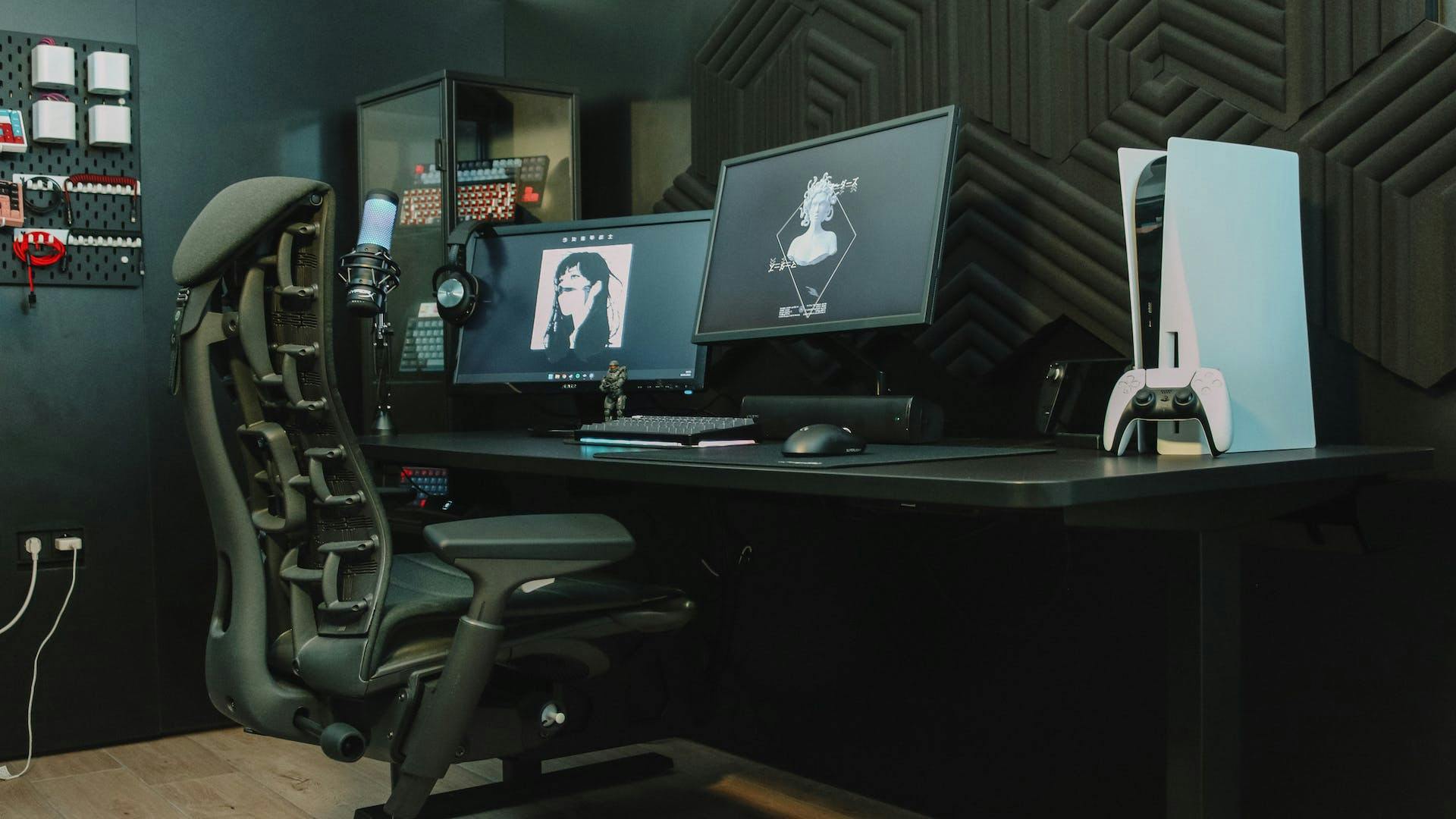 In a dark gaming setup with blue neon accents, a person sits in front of a black gaming PC and Playstation