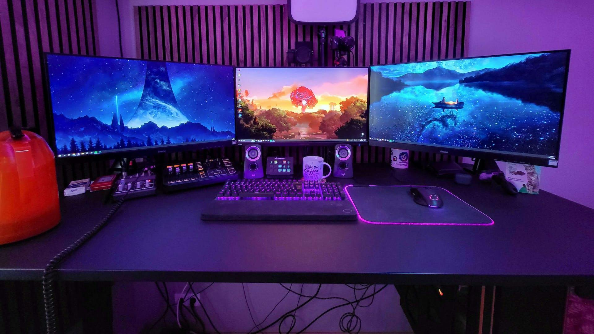 Ein Gaming Setup mit Lila LED Beleuchtung, LeetDesk, drei Monitoren und großer Mausmatte